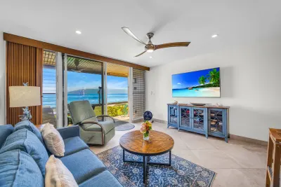 Living room with sofa and smart TV, ocean through the sliding doors