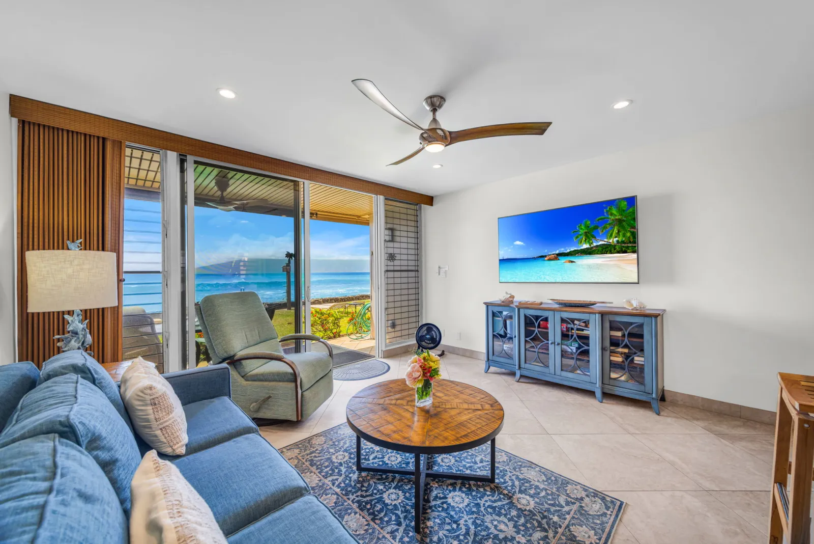 Living room with sofa and smart TV, ocean through the sliding doors