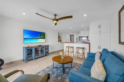 Living room with wall-mounted TV, kitchen beyond